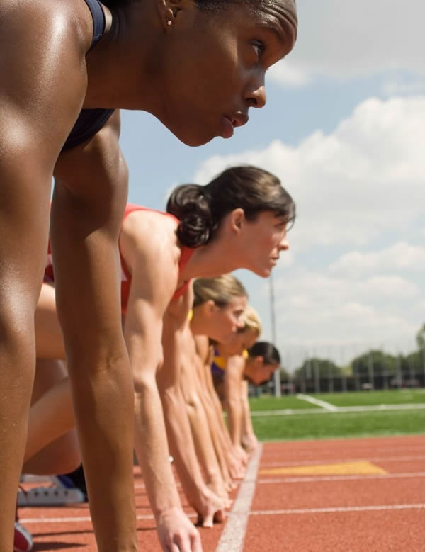 Voici une image de femmes sur les starting blocks sur une piste d'athlétisme.
